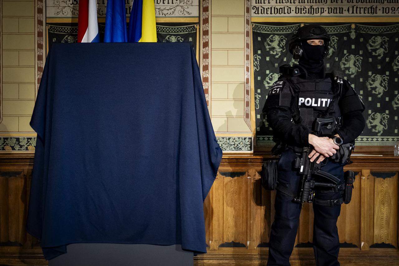 A heavily armed police officer stands next to a display case covered with a cloth, presumably containing the recovered golden helmet by Cotofenesti stolen from the museum in Assen, Netherlands, April 2, 2026. (AFP Photo)