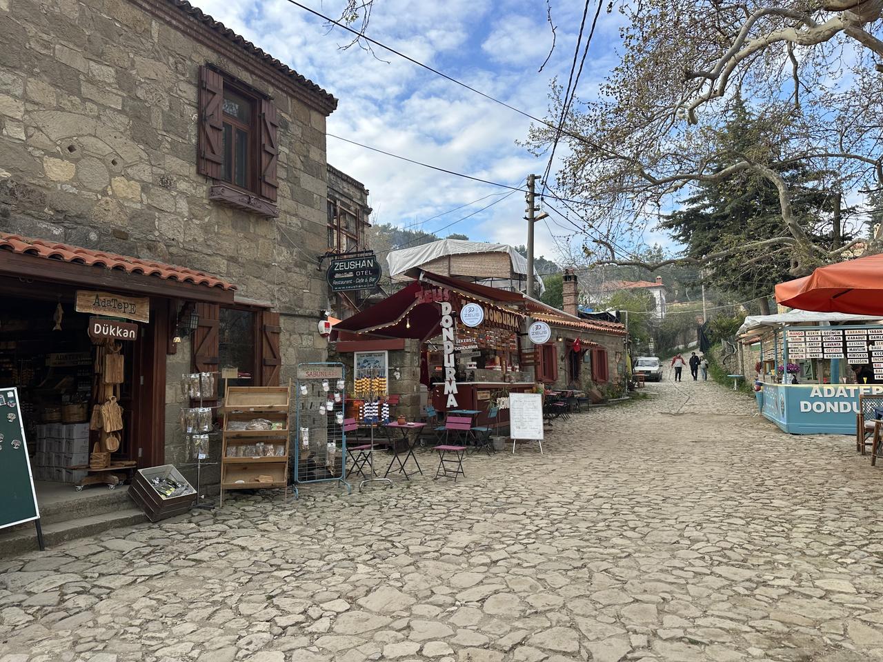 A view of a cobblestone street lined with small shops and cafes in Adatepe village, Canakkale, Türkiye. (AA Photo)
