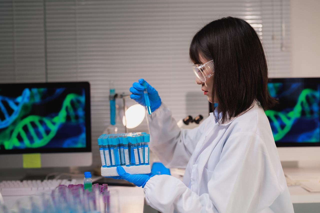 Female scientist analyzing genetic material, holding a test tube with blue liquid in a modern lab (Adobe Stock Photo)