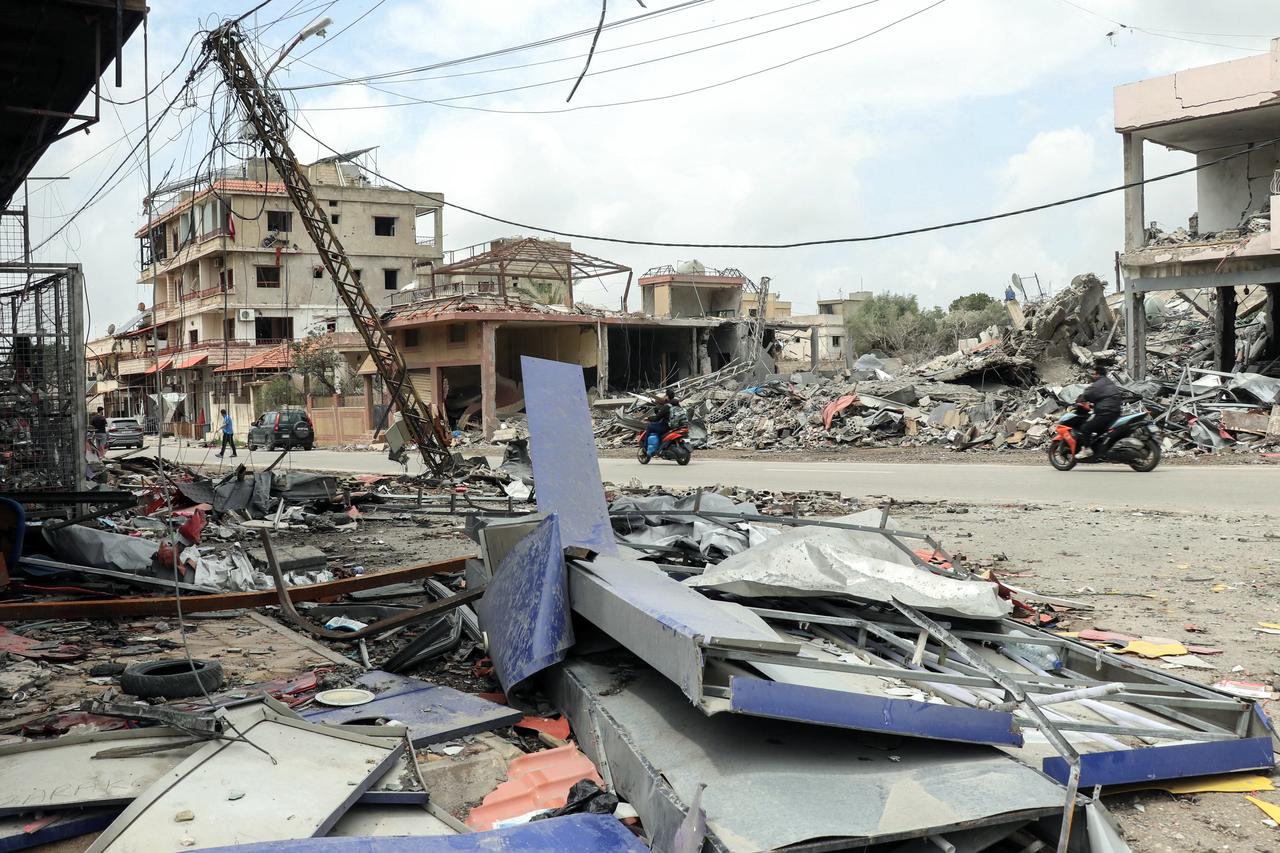 People riding mopeds drive past destroyed buildings as displaced residents return to the southern Lebanese village of Srifa on April 19, 2026. (AFP Photo)