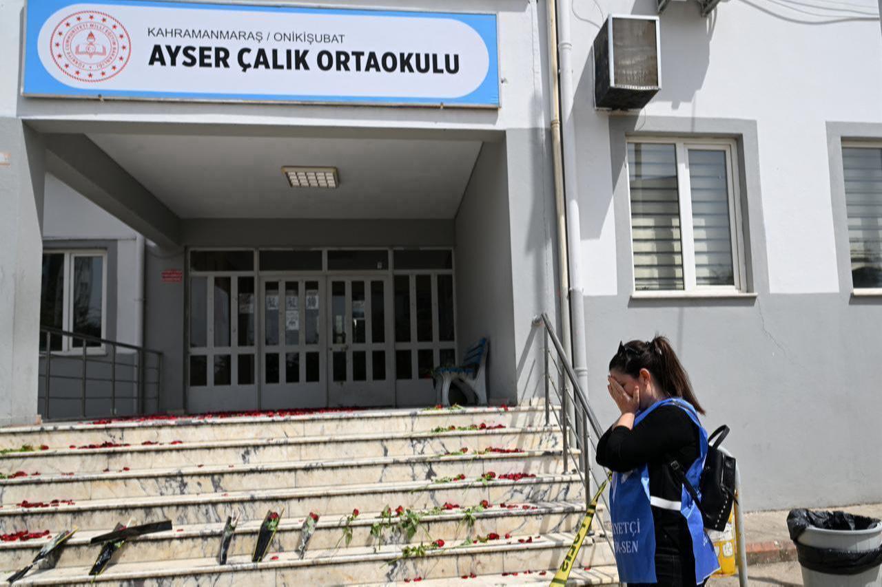 A woman reacts in front of the stairs, where roses are displayed, leading to the entrance of the Ayser Calik college ahead of the funerals for nine victims killed in a school shooting in the southern province of Kahramanmaras, April 16, 2026. (AFP Photo)
