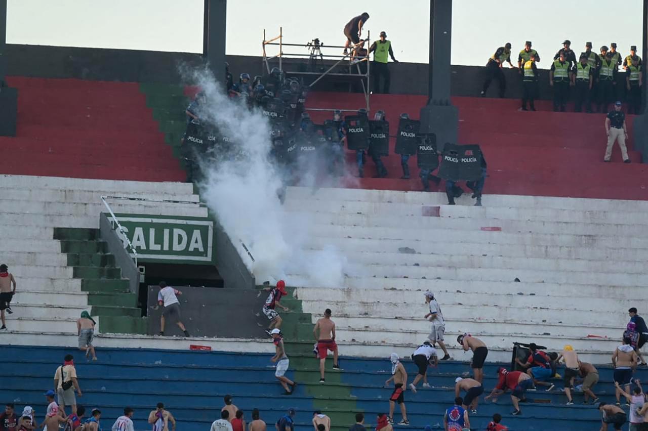 Fans of Cerro Porteno clash with police officers during the Paraguayan tournament football match between Olimpia and Cerro Porteno at the Defensores del Chaco stadium in Asuncion on April 19, 2026. (AFP Photo)