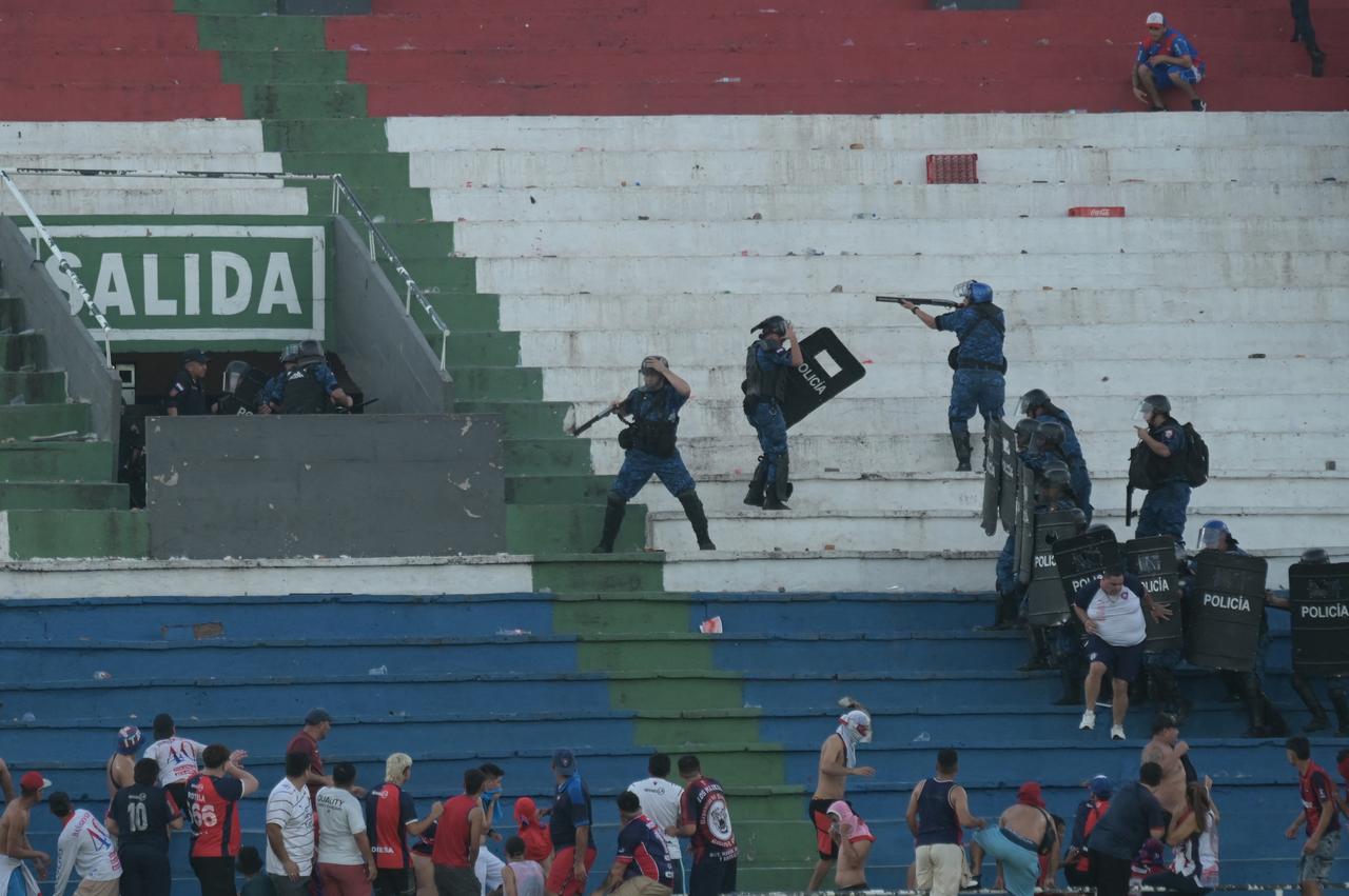 Fans of Cerro Porteno clash with police officers during the Paraguayan tournament football match between Olimpia and Cerro Porteno at the Defensores del Chaco stadium in Asuncion on April 19, 2026.  (AFP Photo)