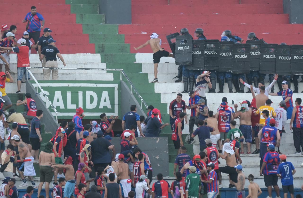 Fans of Cerro Porteno clash with police officers during the Paraguayan tournament football match between Olimpia and Cerro Porteno at the Defensores del Chaco stadium in Asuncion on April 19, 2026. (AFP Photo)