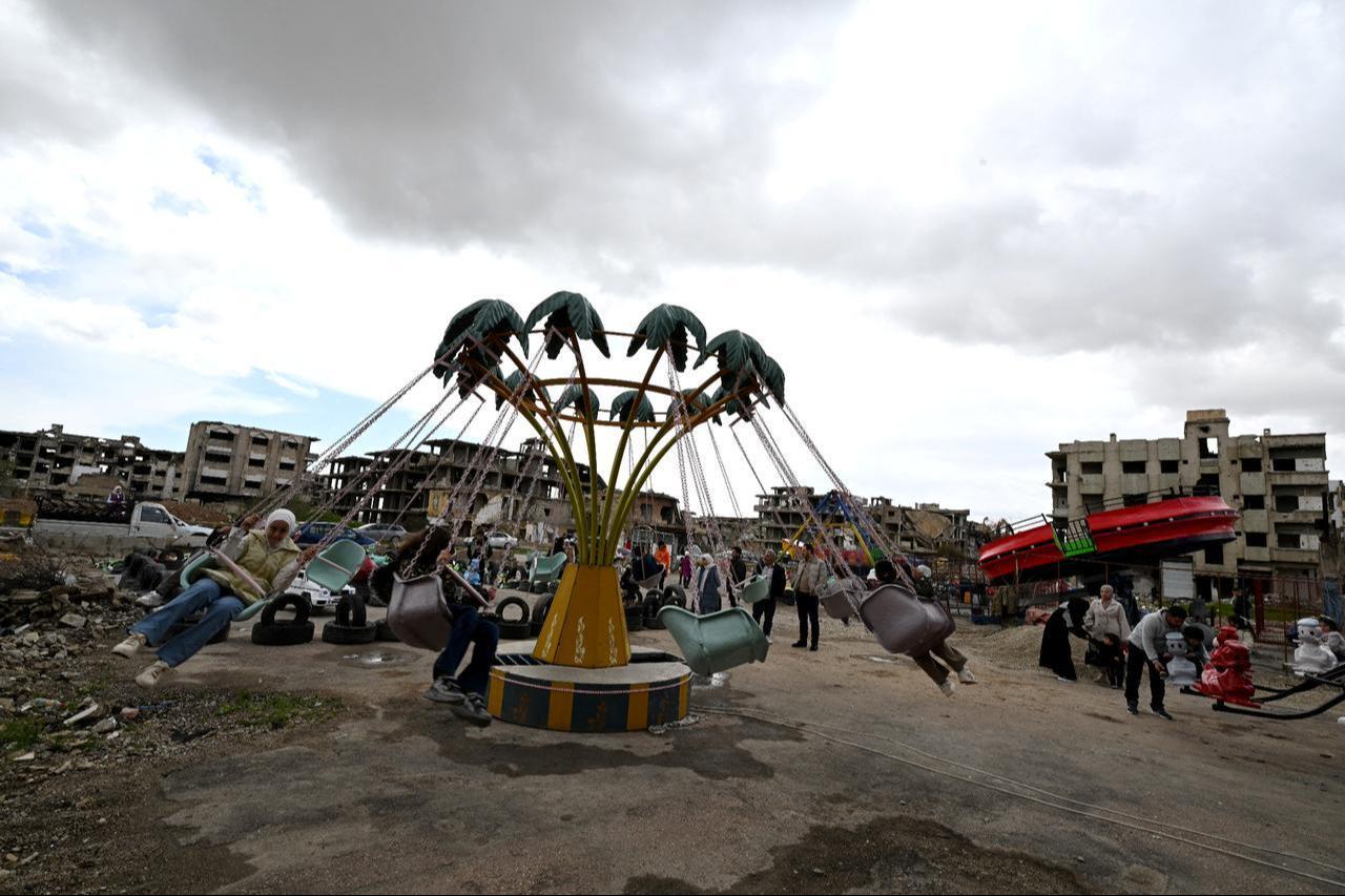 Syrian children enjoy rides at an amusement park set up on land surrounded by destroyed buildings, on the third day of Eid al-Fitr, marking the end of the holy fasting month of Ramadan, in the Jobar neighborhood of Damascus on March 22, 2026. (AFP Photo)