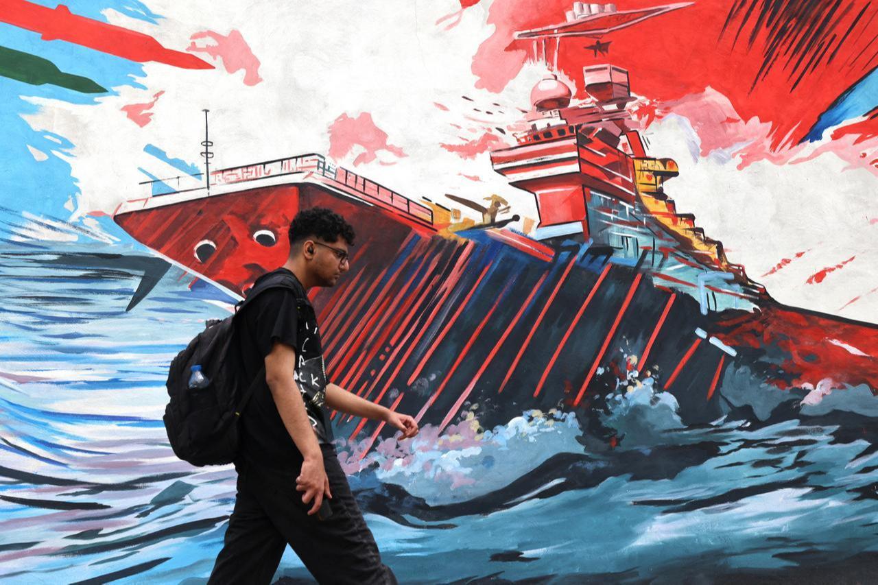 An Iranian man walks past an anti-USA and anti-Israel mural in Tehran on April 21, 2026, amid a ceasefire in the region. (AFP Photo)