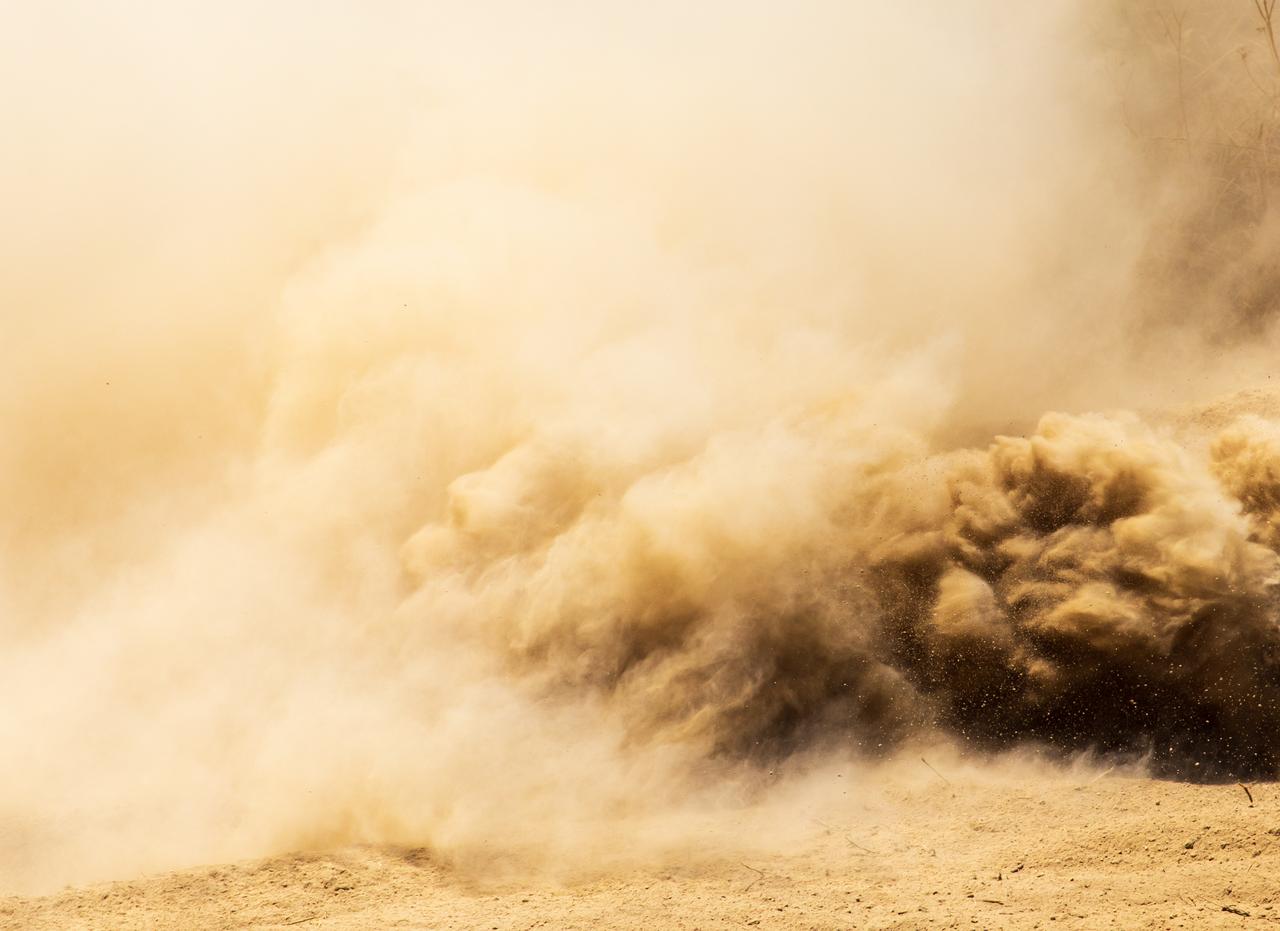 A massive dust cloud sweeps across a natural landscape. (Adobe Stock Photo)
