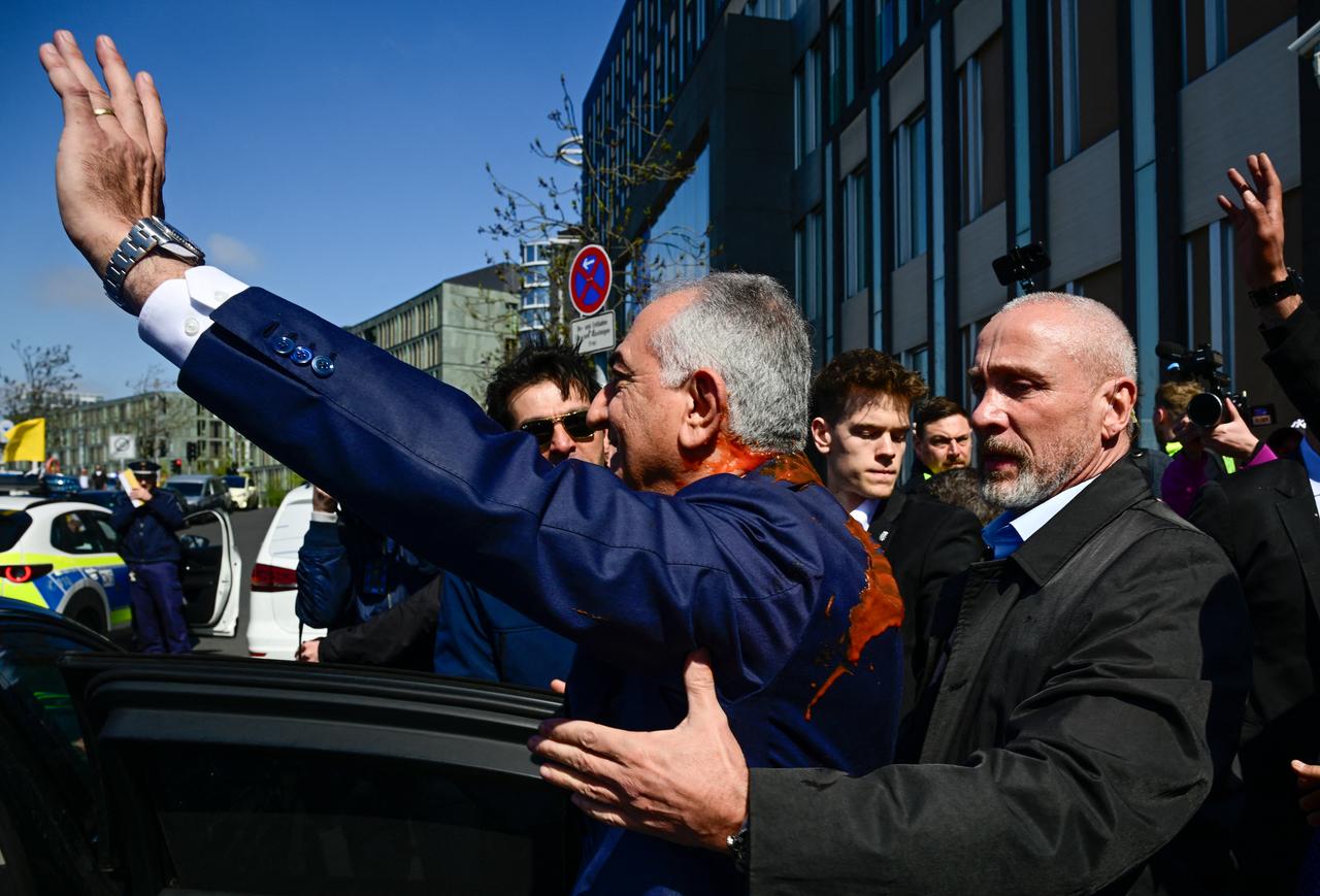 Security brings son of Iran's last shah, exiled Crown Prince Reza Pahlavi into a car after he was splashed with red liquid by an activist in Berlin, April 23, 2026. (AFP Photo)