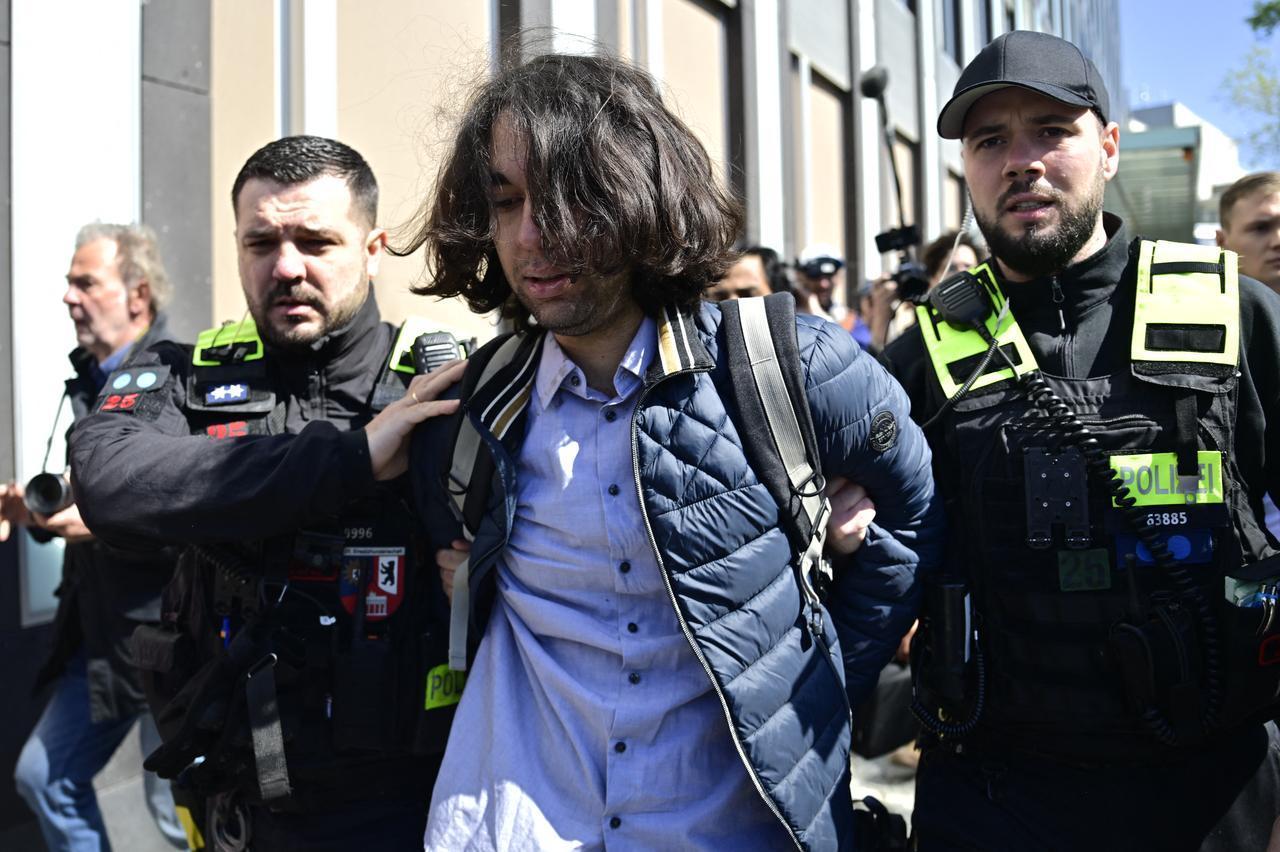 An activist (C) is detained by police after he splashed red liquid on the back of the son of Iran's last shah, exiled Crown Prince, after a press conference in Berlin, April 23, 2026. (AFP Photo)