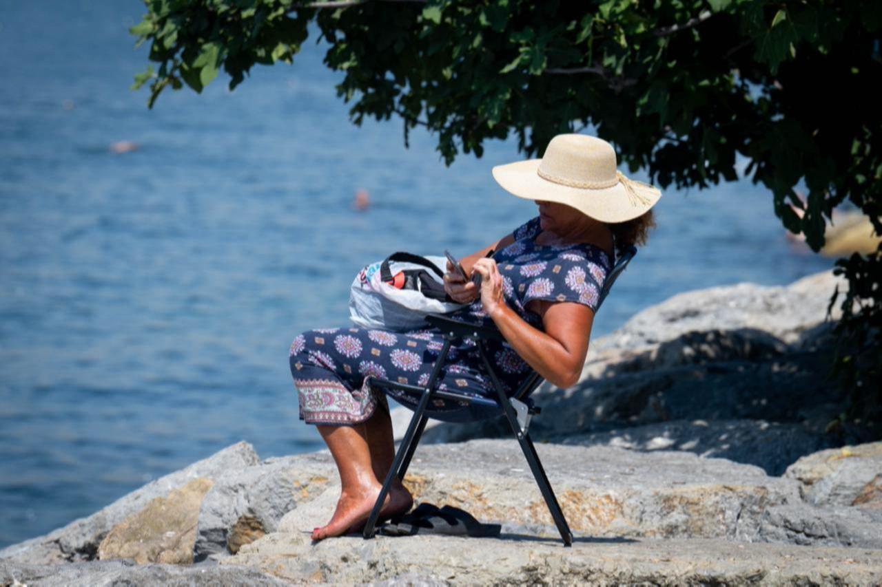 A woman protecting herself from the sun with a hat spends time at the Uskudar Salacak beach on a hot summer day in Istanbul, Türkiye, July 23, 2025. (AA Photo)