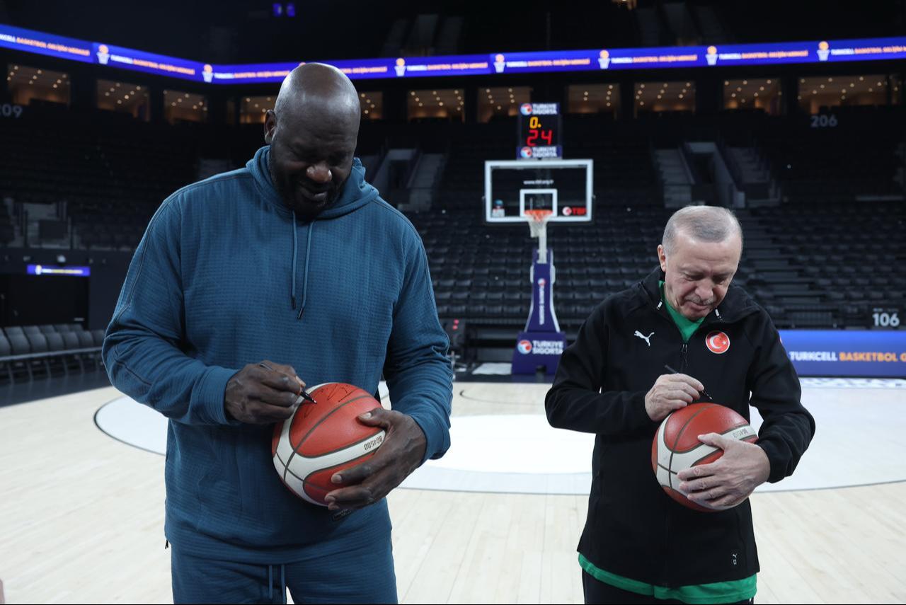 Shaquille O'Neal and President Erdogan sign basketballs during their meeting on the court, sharing a light moment at the basketball venue in Istanbul, Türkiye, Jan. 20, 2026. (Photo via X/@RTErdogan)