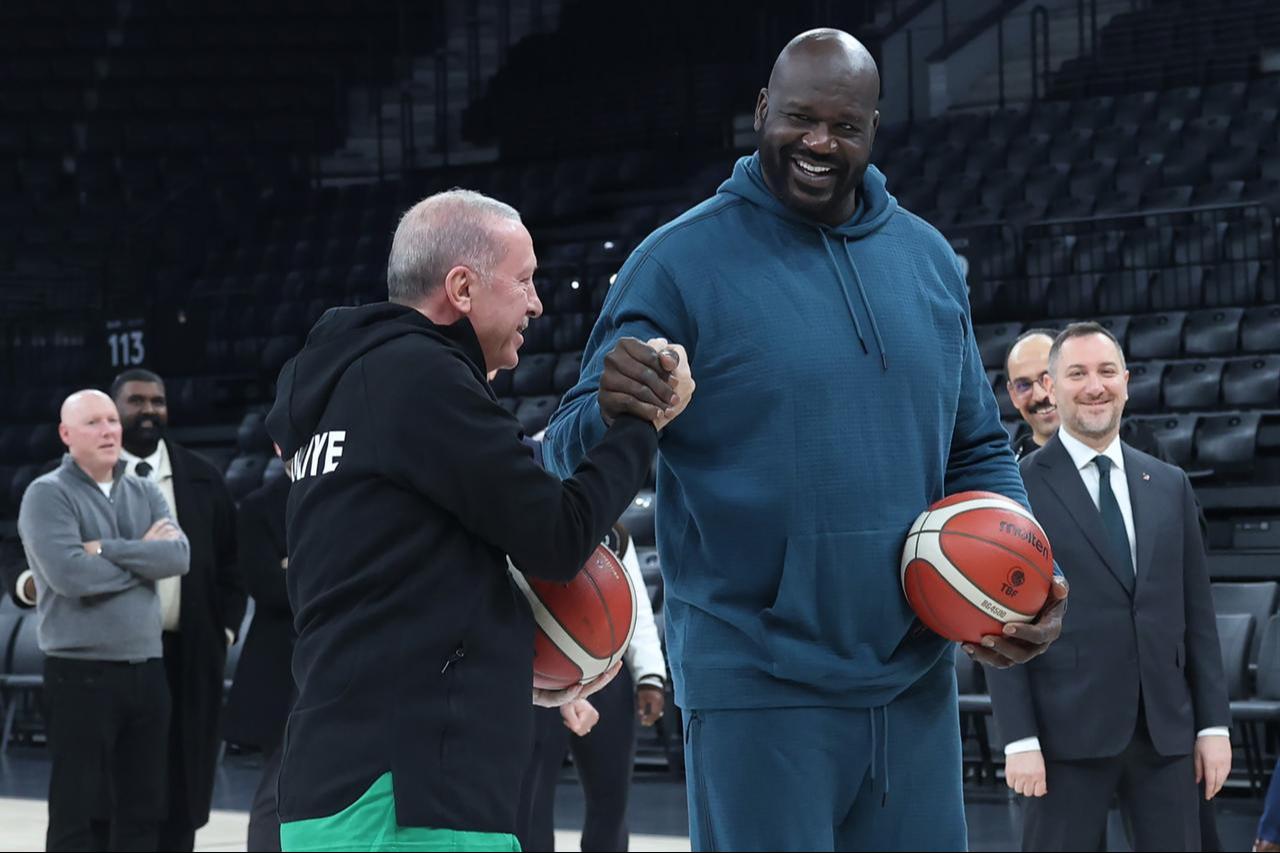 President Erdogan shakes hands with Shaquille O'Neal while holding basketballs, as officials look on during the former NBA star’s visit to the Turkcell Basketball Development Center in Istanbul, Türkiye, Jan. 20, 2026. (Photo via X/@RTErdogan)