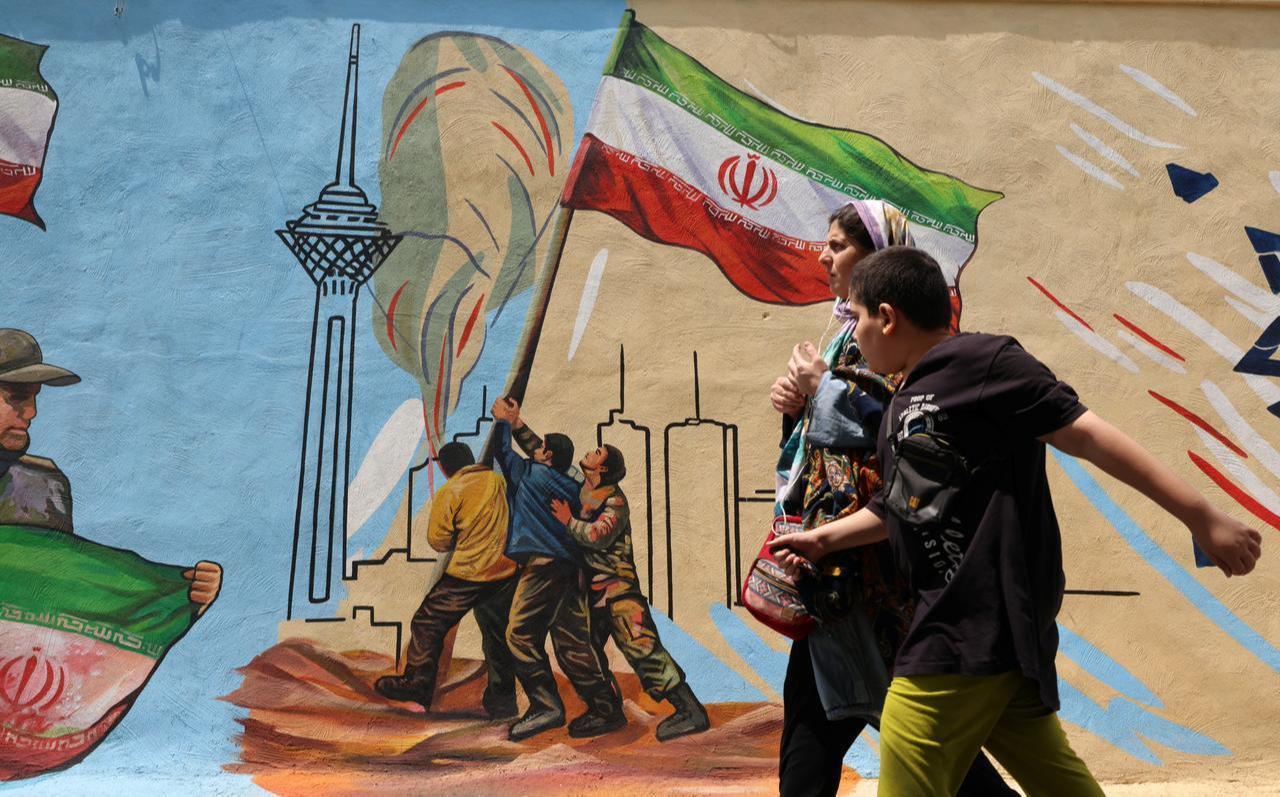 A woman and boy walk past a nationalistic mural, in Tehran on April 21 2026, amid a ceasefire in the region. (AFP Photo)