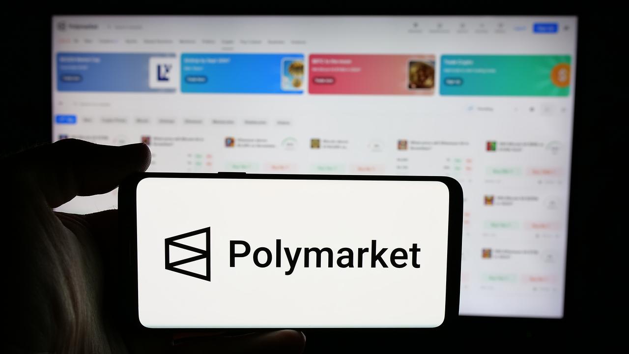 Person holding a cellphone with the logo of the crypto prediction market company Polymarket on the screen in front of a business webpage in Stuttgart, Germany, Nov. 27, 2024. (Adobe Stock Photo)