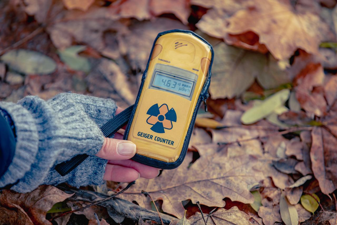 A person checks radiation levels using a handheld dosimeter in Pripyat, within the Chernobyl Exclusion Zone, Ukraine. (Adobe Stock Photo)