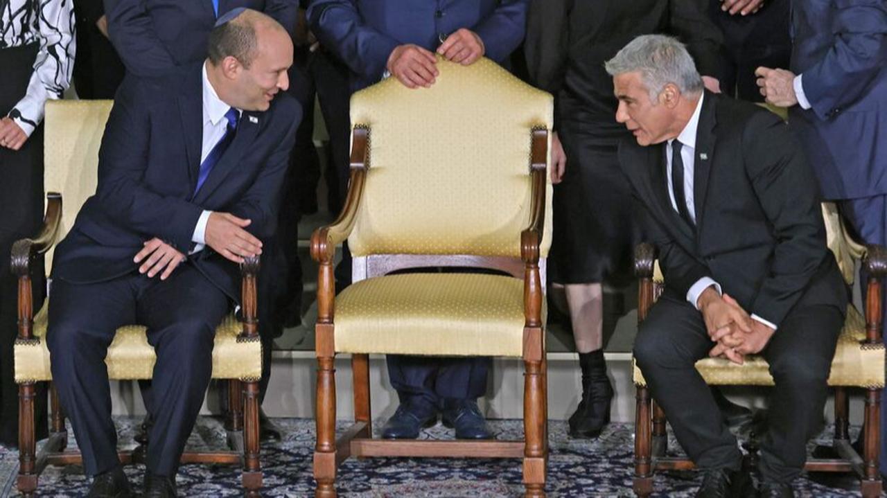 Naftali Bennett (L) and Yair Lapid chat ahead of a photo of the new coalition government at the president's residence in Jerusalem, on June 14, 2021. (AFP Photo)