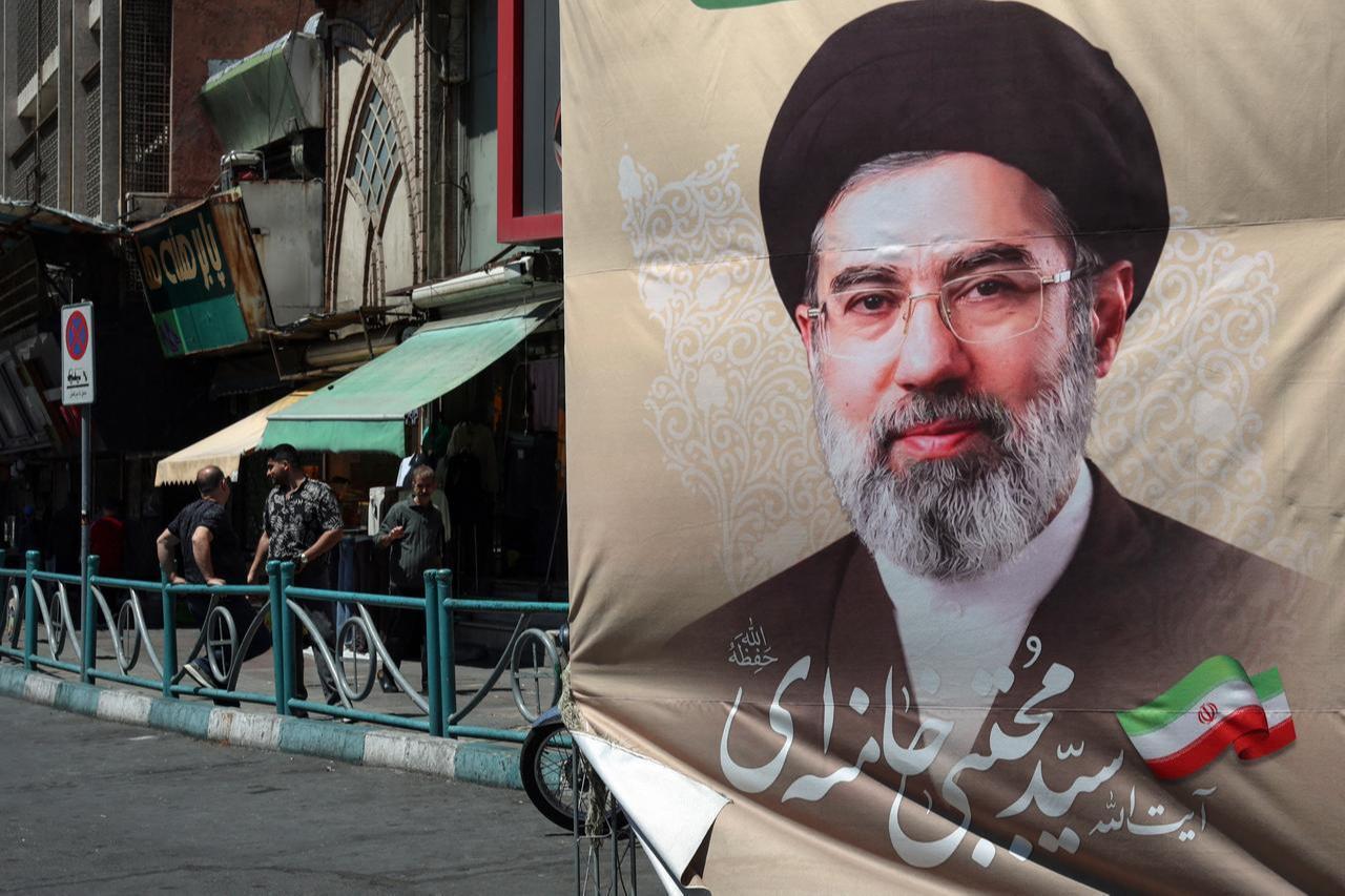 Iranians stand on a pavement along a street next to a billboard depicting Iran's Supreme Leader Mojtaba Khamenei, in Tehran on April 24, 2026. (AFP Photo)