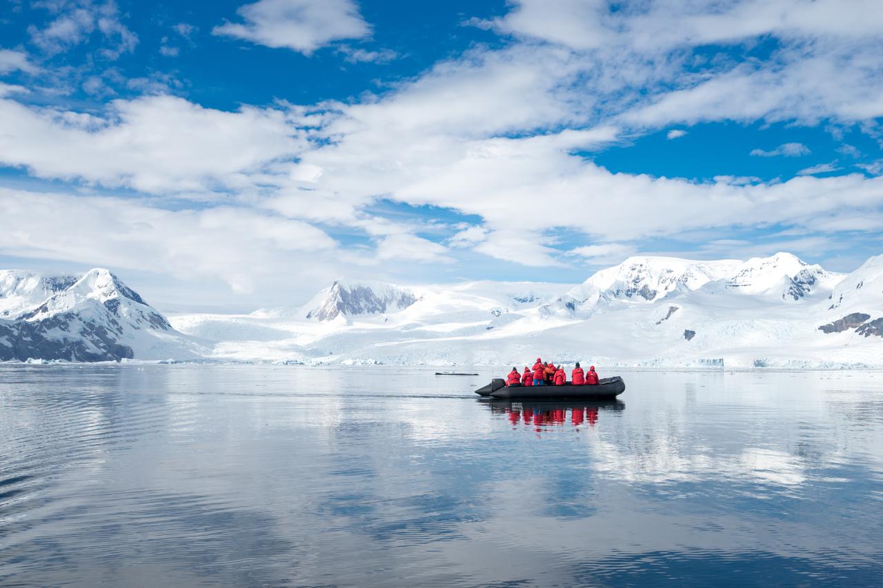 Inflatable boat full of tourists, watching for whales and seals, Antarctic Peninsula, Antarctica. (Adobe Stock Photo)