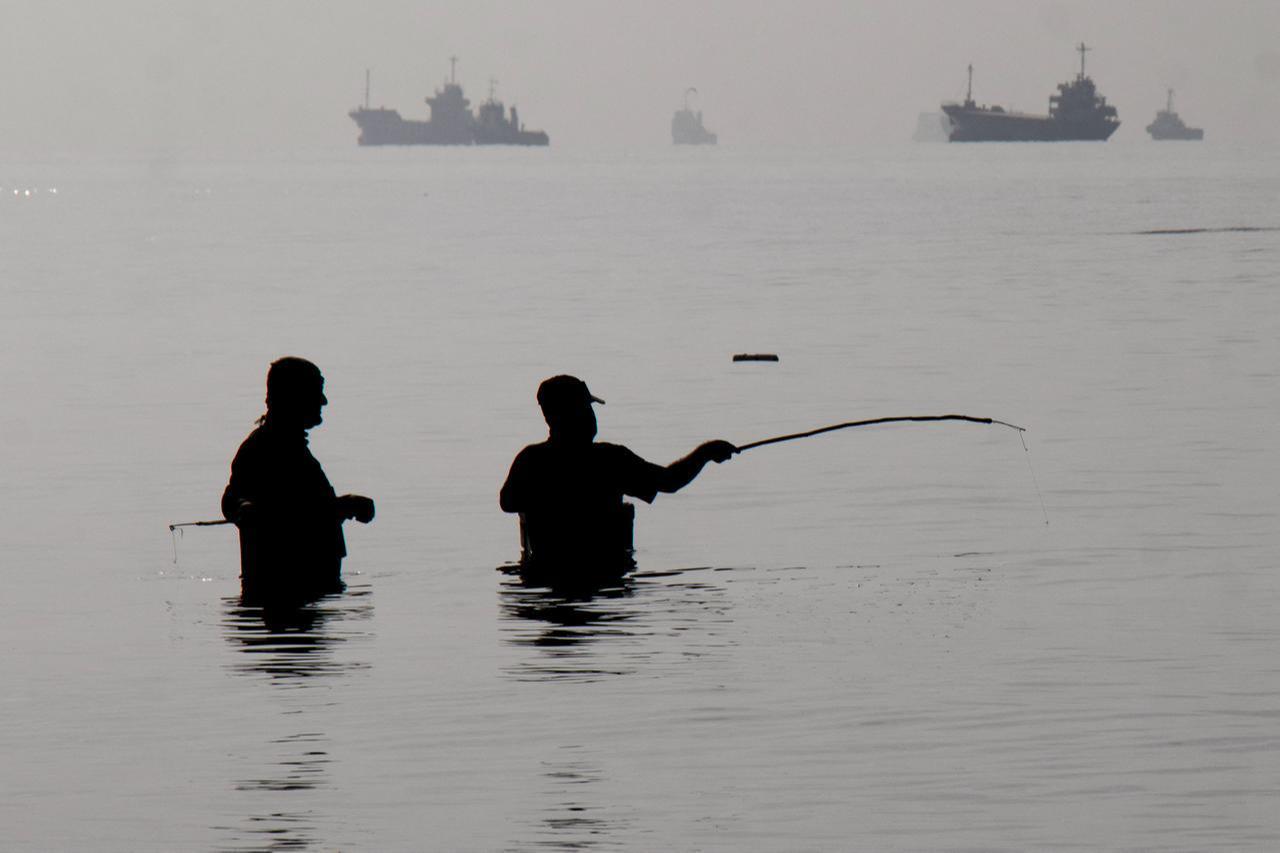 In this picture obtained from Iran's ISNA news agency on April 24, 2026, Iranian men fish at Suru Beach in Bandar Abbas along the Strait of Hormuz. (AFP Photo)