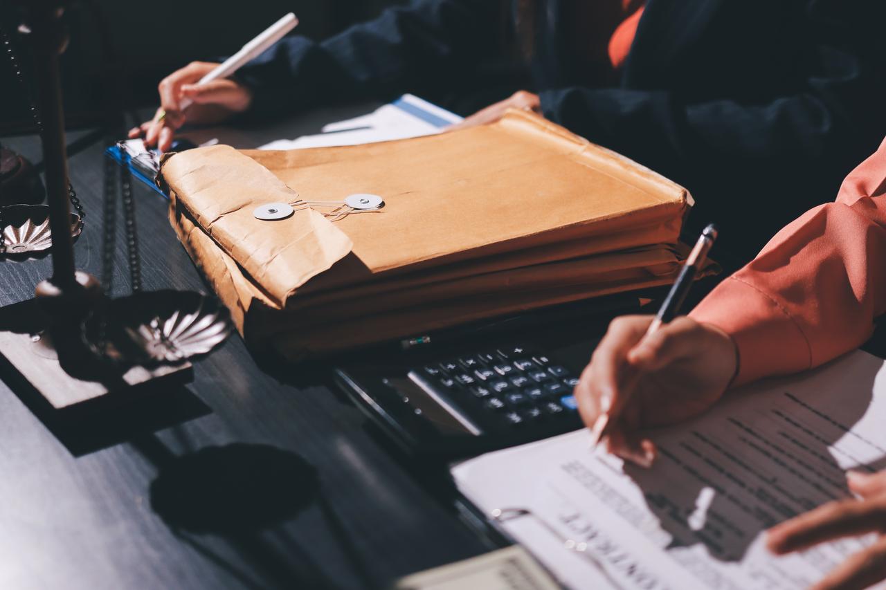 People review documents and case files on a desk (Adobe Stock Photo)