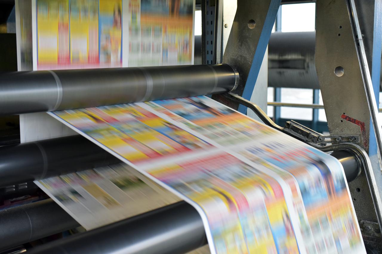 An offset printing machine prints colored newspapers at a printing press (Adobe Stock Photo)