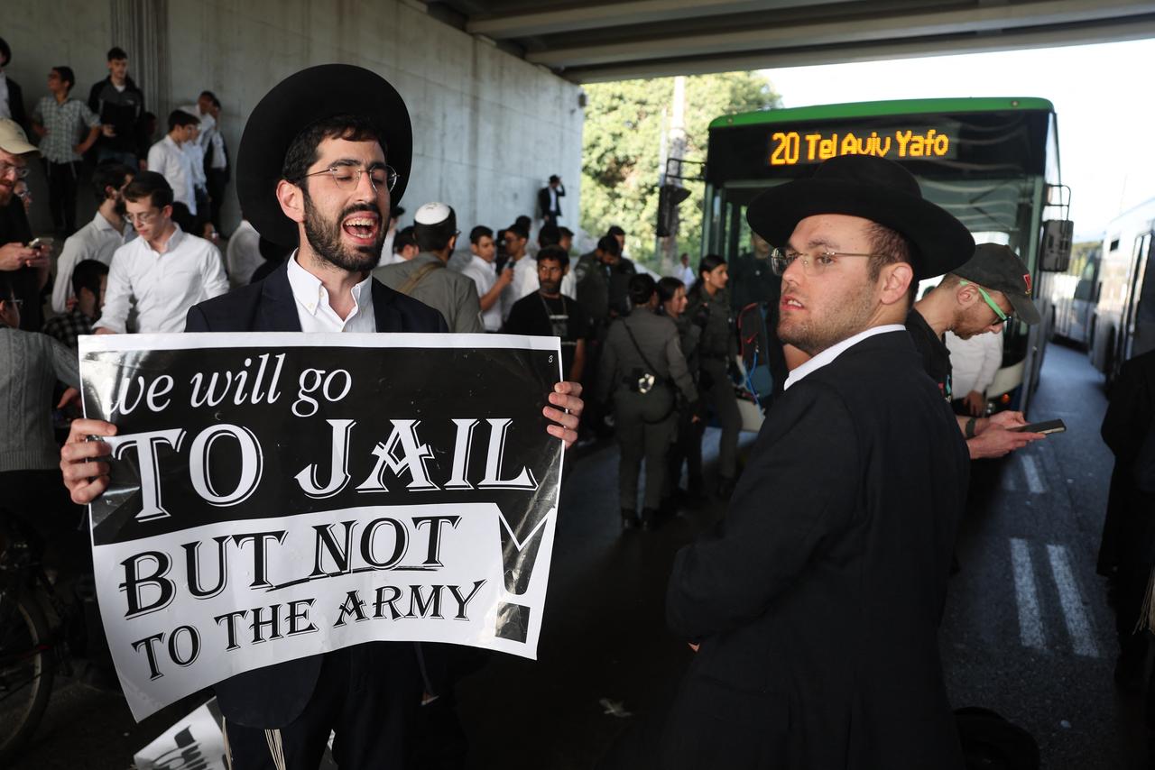 An Ultra-Orthodox Jew, who is largely exempt from military service, holds a placard while protesting with others against conscription by blocking a highway near the centre of the Israeli city of Bnei Brak on April 28, 2026. (AFP Photo)