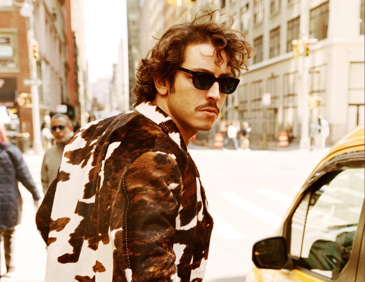 Boran Kuzum poses on a city street beside a yellow taxi, New York, United States, April 29, 2026. (Courtesy of BKM)