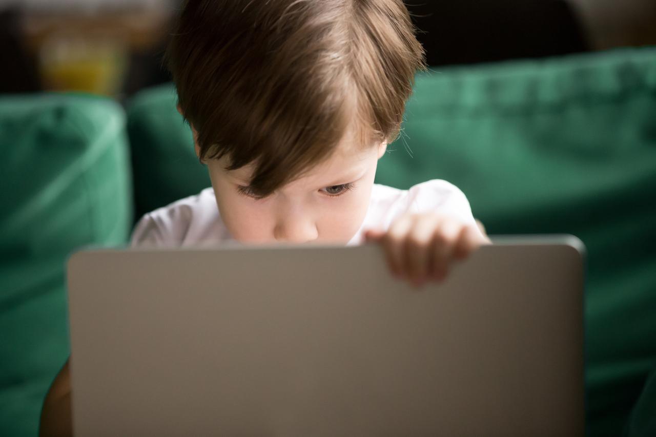 A young boy using a laptop at home, representing concerns about children’s exposure to inappropriate online content. (Adobe Stock Photo)