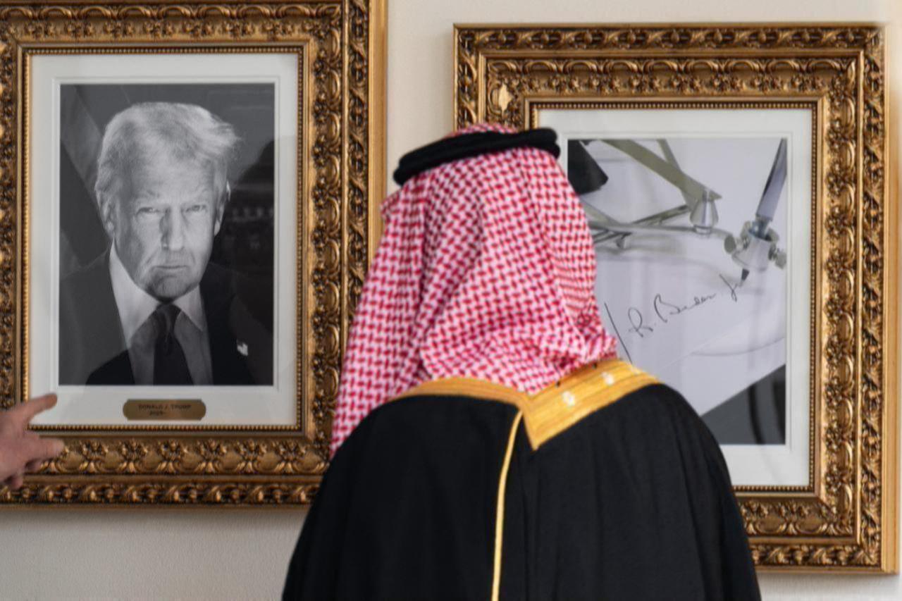 Crown Prince and PM of the Kingdom of Saudi Arabia Mohammed bin Salman looks at a framed photo of US President Donald Trump (L) next to a picture of an autopen (R) as he walks down the Colonnade on the way to the Oval Office in Washington, DC on Nov. 18, 2025. (AFP Photo)