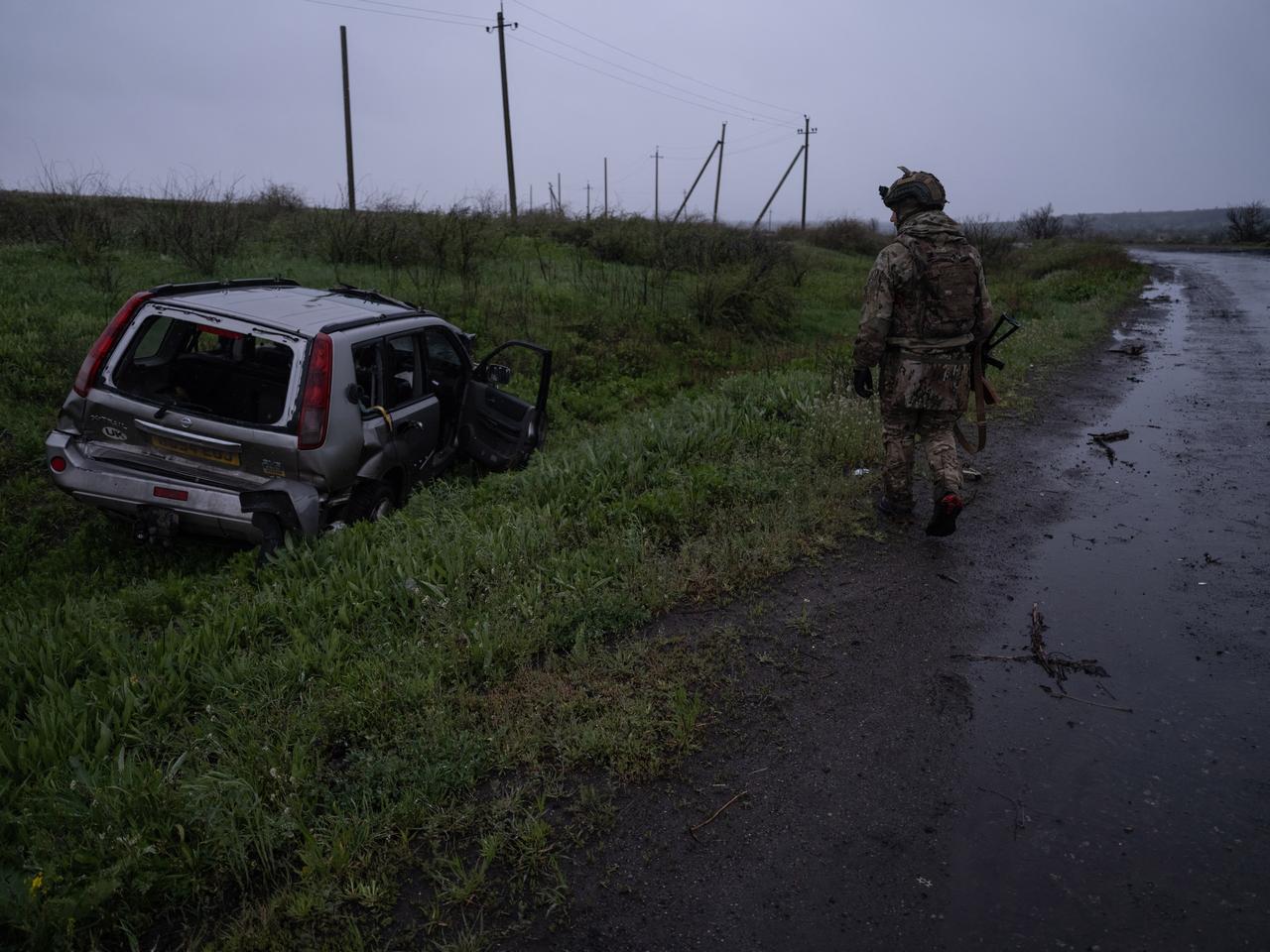 In this handout photograph released on April 25, 2026, a Ukrainian serviceman walks on a road past a damaged vehicle, near Druzhkivka, in the Donetsk region. (Photo by IRYNA RYBAKOVA/The 93rd Kholodnyi Yar Separate/AFP)
