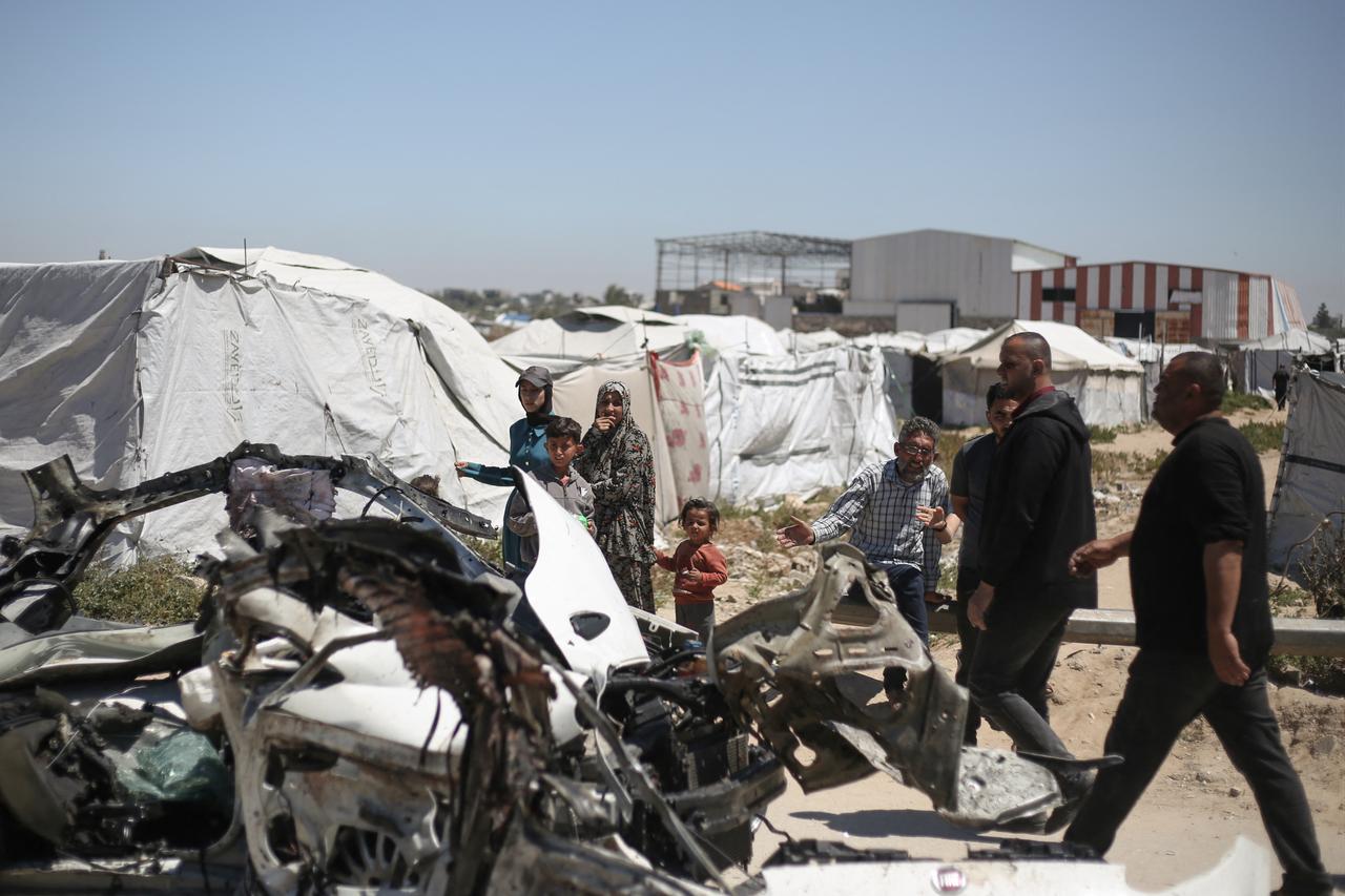 People inspect a destroyed civilian vehicle after it was targeted by an Israeli airstrike that allegedly killed three people on Salah al-Din Street, south of Bureij camp for Palestinian refugees in the central Gaza Strip, April 23, 2026. (AFP Photo)