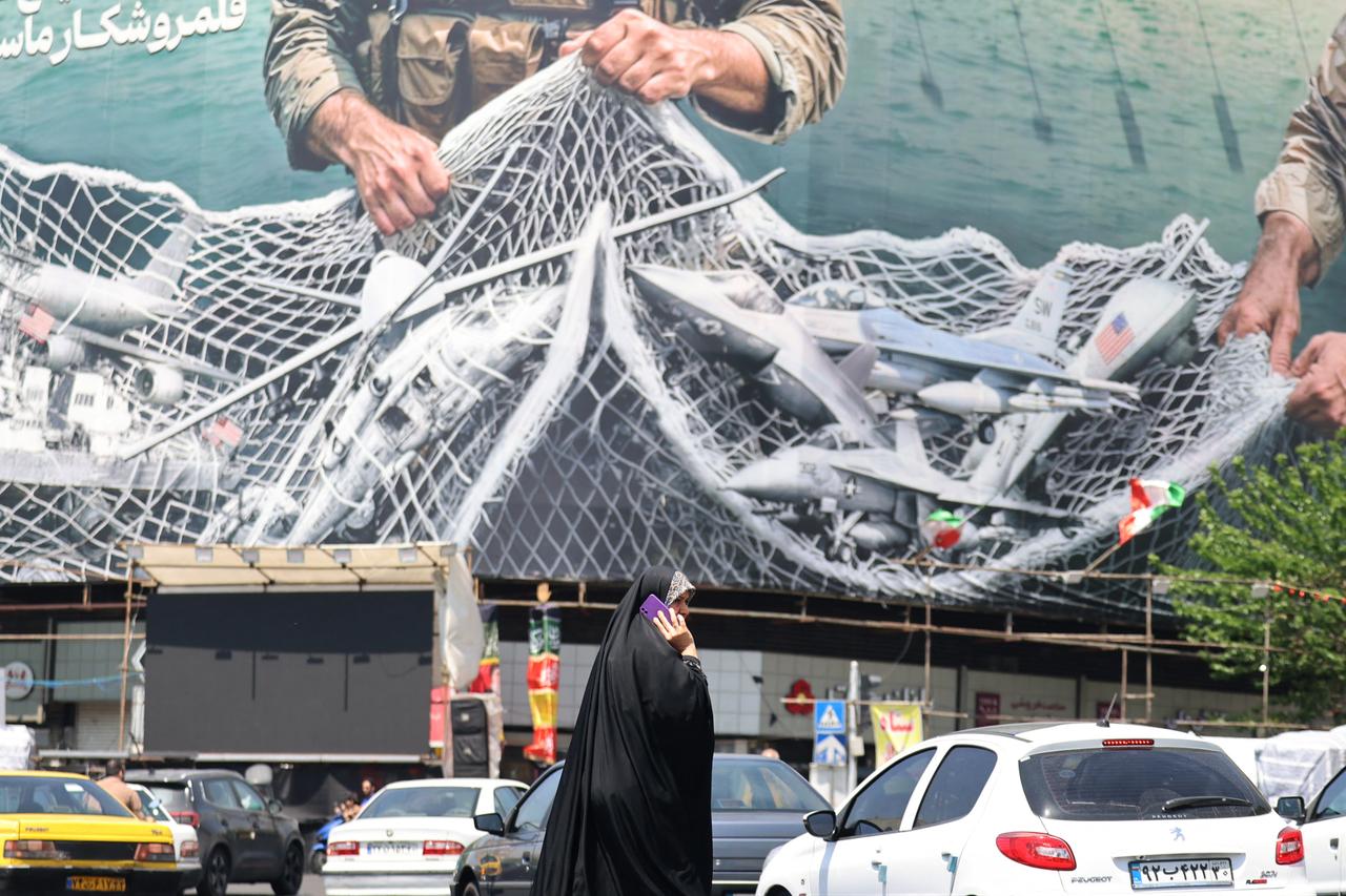 A woman walks past a giant billboard reading "The Strait of Hormuz remains closed" at the Revolution Square in Tehran on April 28, 2026. (AFP Photo)