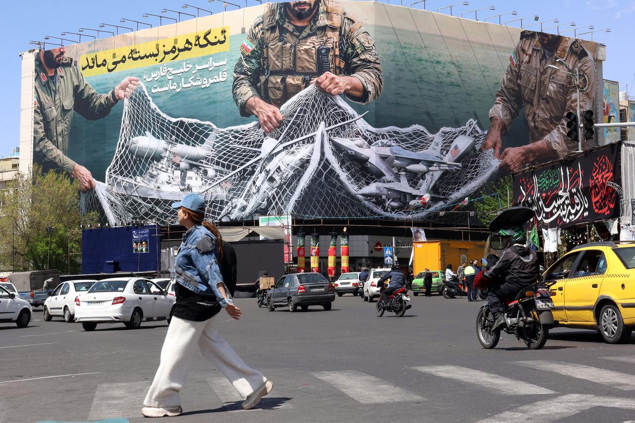 Commuters make their way past a billboard with a sentence reading ‘The Strait of Hormuz remains closed’ at the Enqelab Square in Tehran, on April 5, 2026. (AFP Photo)