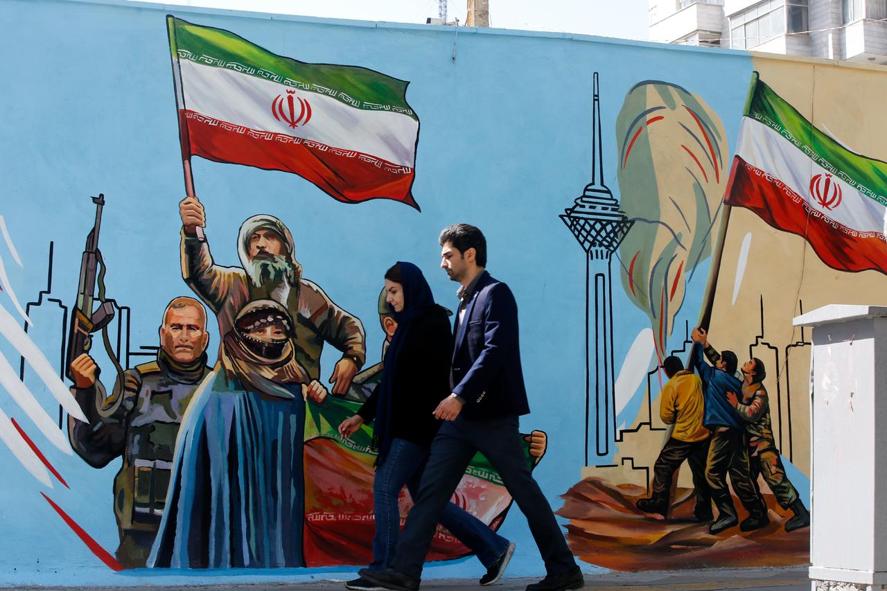 Residents walk past colorful wall paintings as daily life continues under the shadow of destruction following the U.S. and Israeli attacks on Tehran, Iran, April 5, 2026. (AA Photo)