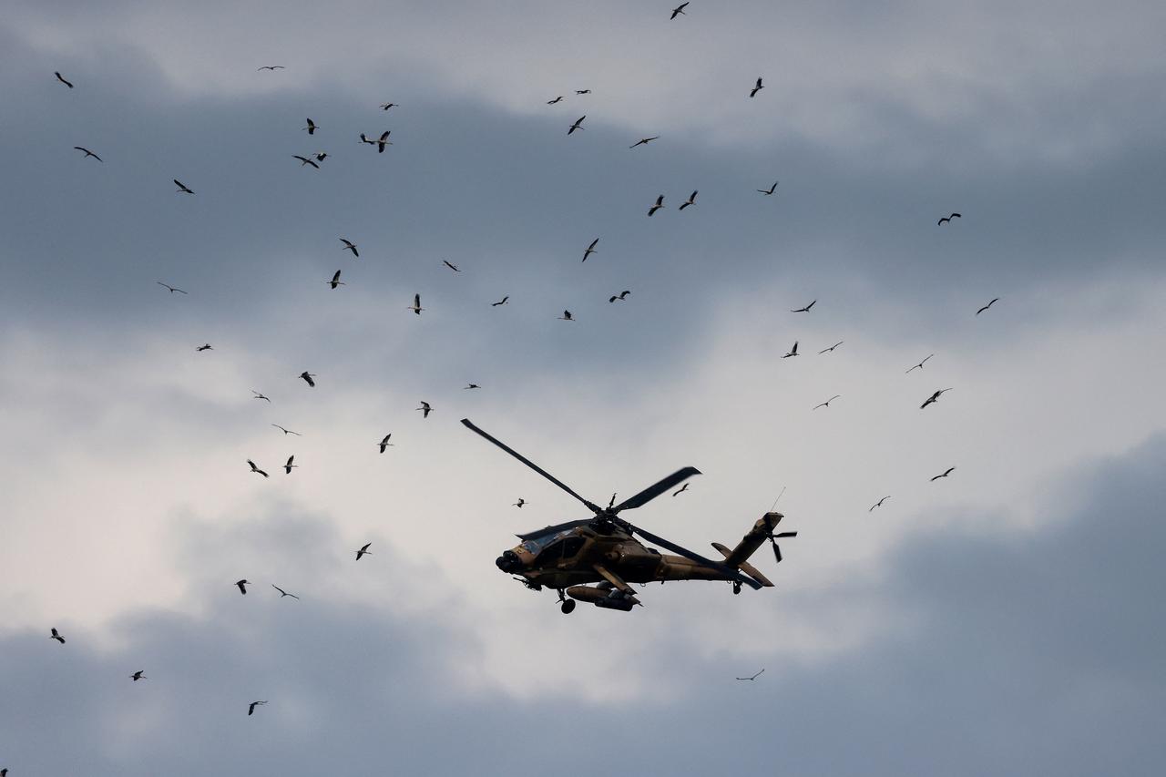 An Israeli helicopter gunship flying along the Lebanon–Israel border in the Upper Galilee crosses the path of migrating white storks (Ciconia ciconia), over northern Israel on March 22, 2026. (AFP Photo)