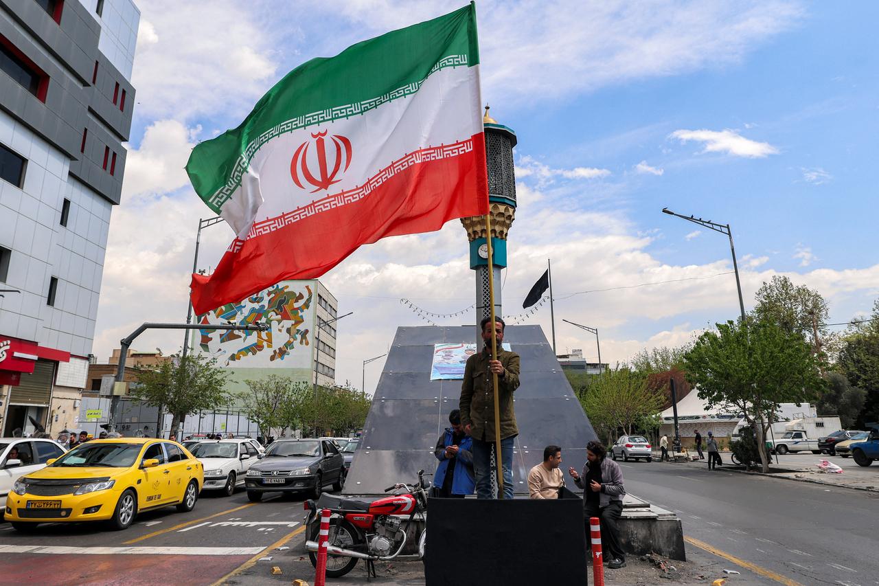 A man stands with an Iranian national flag along an intersection at Valiasr Square in Tehran on April 6, 2026. (AFP Photo)