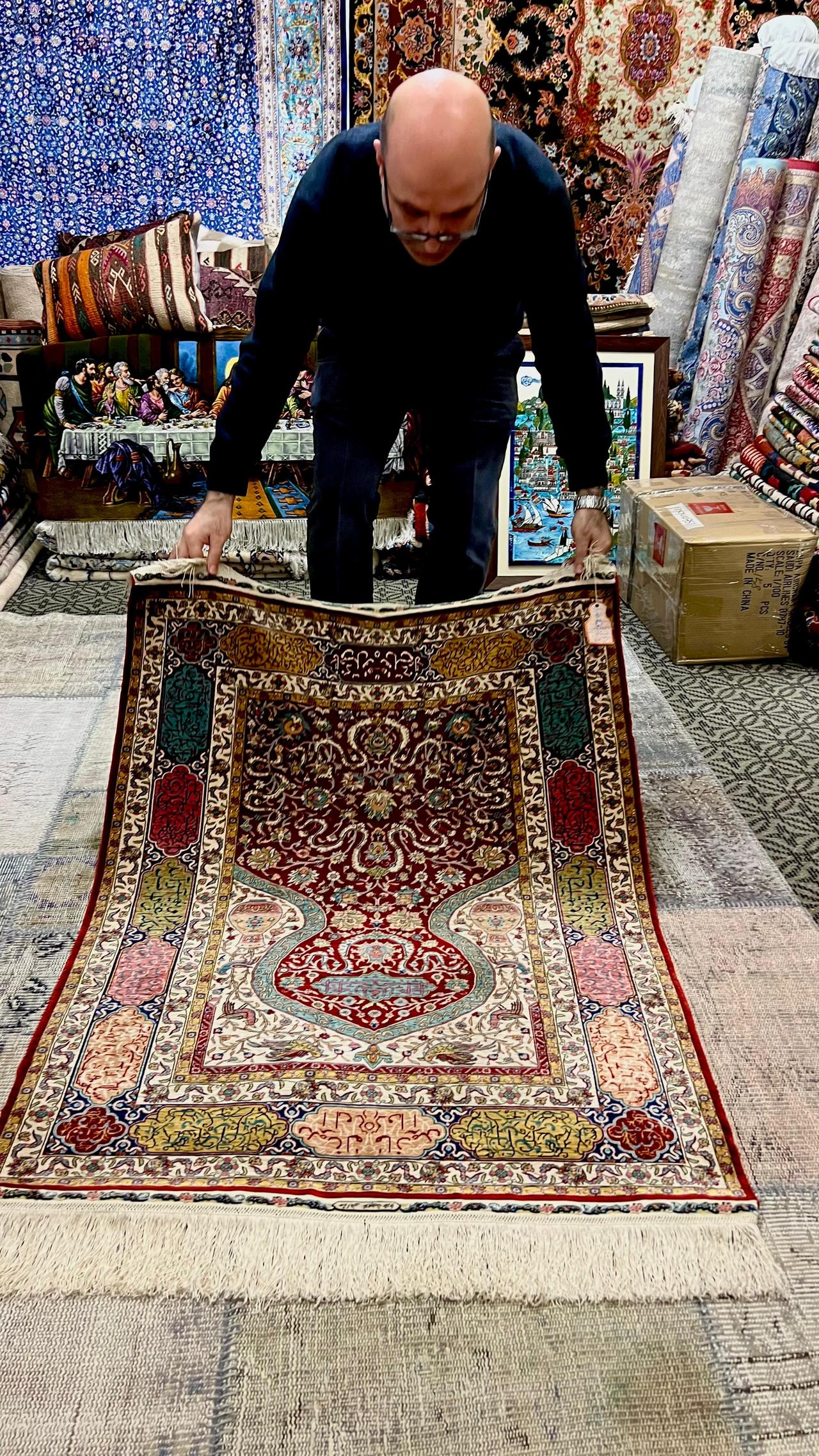 Demonstrating a Hereke carpet’s magic where colors shift from light to dark as the rug turns (Photo by Türkiyetoday)