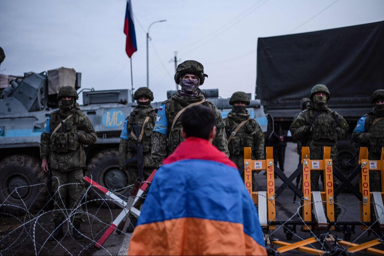 A protester wearing the Armenian national flag stands in front of Russian peacekeepers blocking the road outside Stepanakert, capital of the self-proclaimed Nagorno-Karabakh region of Azerbaijan, December 24, 2022. (AFP Photo)