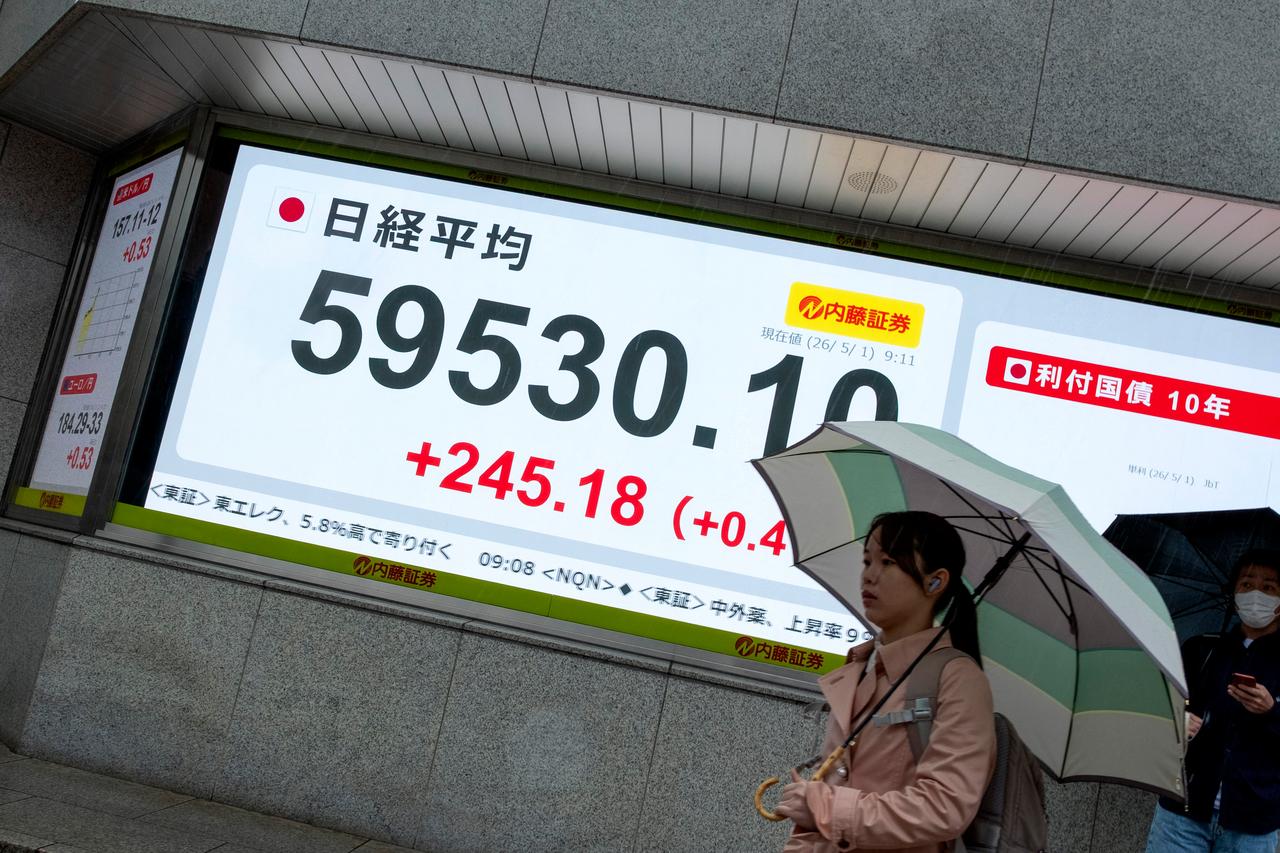 A woman walks past an electronic quotation boards displaying the Nikkei Stock Average on the Tokyo Stock Exchange along a street in Tokyo, May 1, 2026. (AFP Photo)