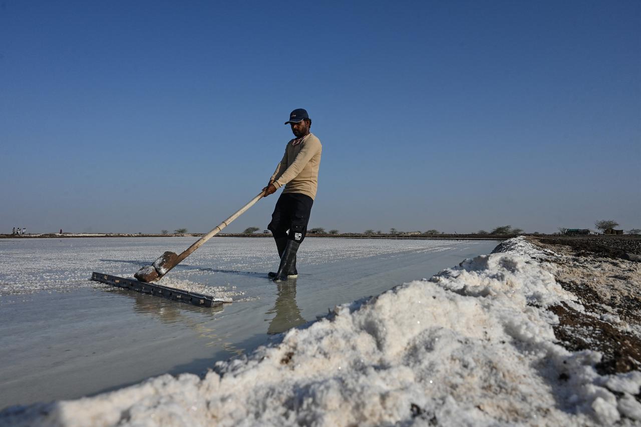 A salt pan worker raking harvested salt at an alkali flat in the Little Rann of Kutch region in Gujarat. India on April 29, 2026 (AFP Photo)