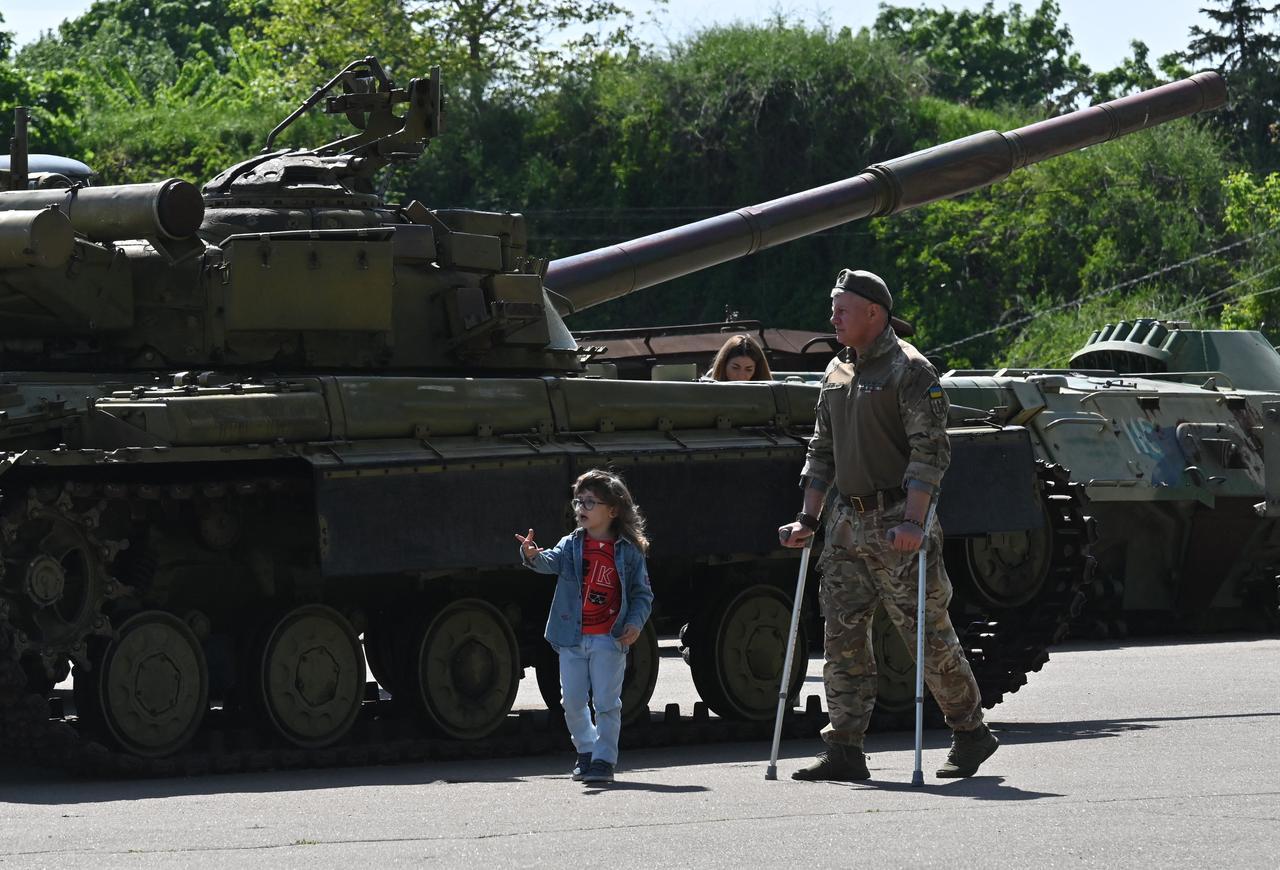 A wounded Ukrainian serviceman and his daughter walk next to a tank as they visit the National Museum of the History of Ukraine in World War II, in Kyiv on May 9, 2026. (AFP Photo)