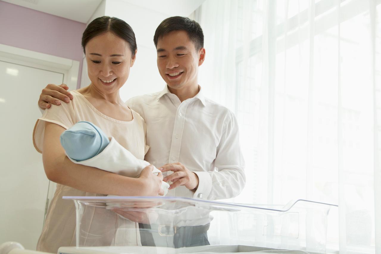 Parents look at their newborn baby in a hospital room. (Adobe Stock Photo)