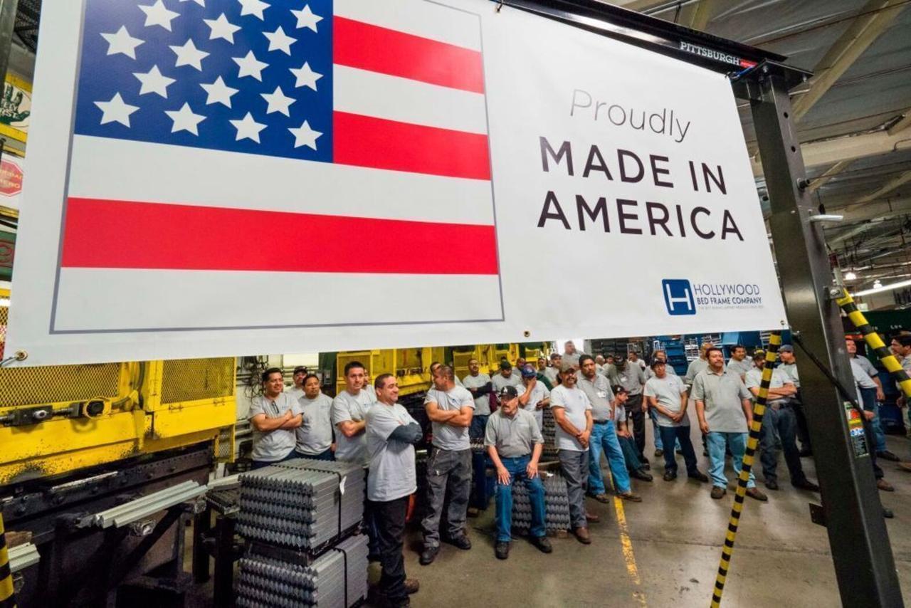 This photo depicts workers in a factory setting, likely at a company manufacturing metal products such as bed frames, as indicated by the "Hollywood Bed Frame Company" sign. (AFP Photos)