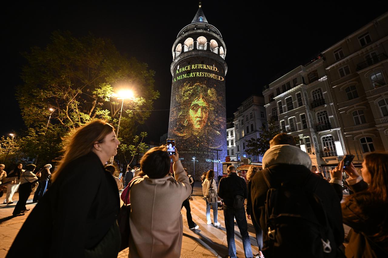 Visitors watch a projection mapping display on the historic Galata Tower in Istanbul as part of an awareness campaign on protecting cultural heritage and preventing artifact trafficking, May 13, 2026. (AA Photo)