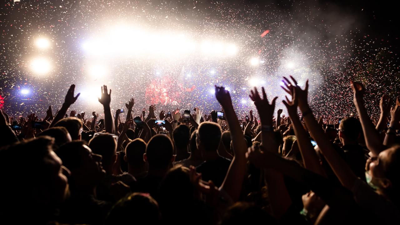 Concertgoers raise their hands as confetti fills the air during a live music performance. (Adobe Stock Photo)