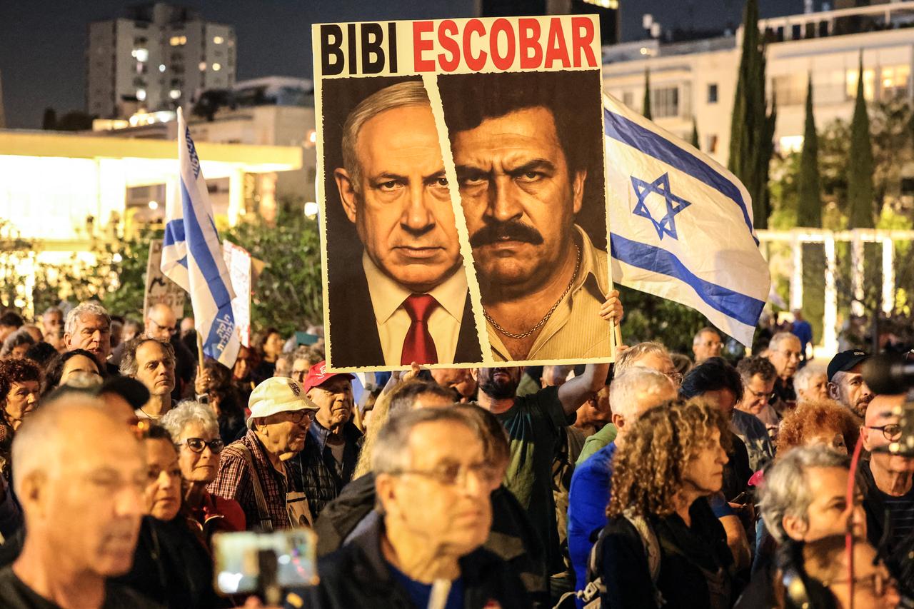 A demonstrator holds a sign depicting a mashup of the faces of Israeli Prime Minister Benjamin Netanyahu and late Colombian drug lord Pablo Escobar during a rally in Tel Aviv's HaBima Square against the ongoing war with Iran and against the Israeli government on May 9, 2026. (AFP Photo)