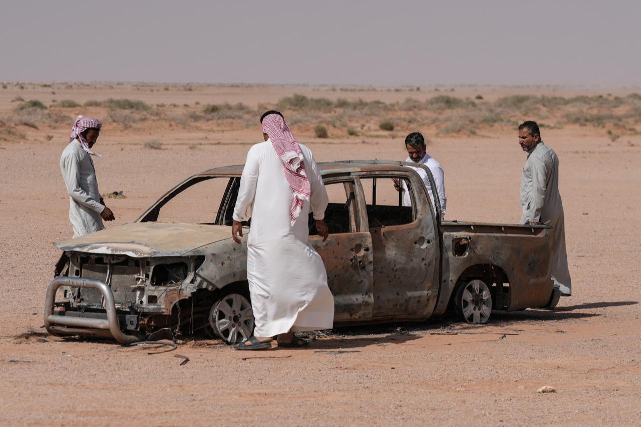 Men gather around the husk of a destroyed pickup truck that was driven by a local shepherd, and who was reportedly struck by Israeli forces and buried by locals at a grave nearby, in Najaf desert in southwestern Iraq, May 12, 2026. (AFP Photo)