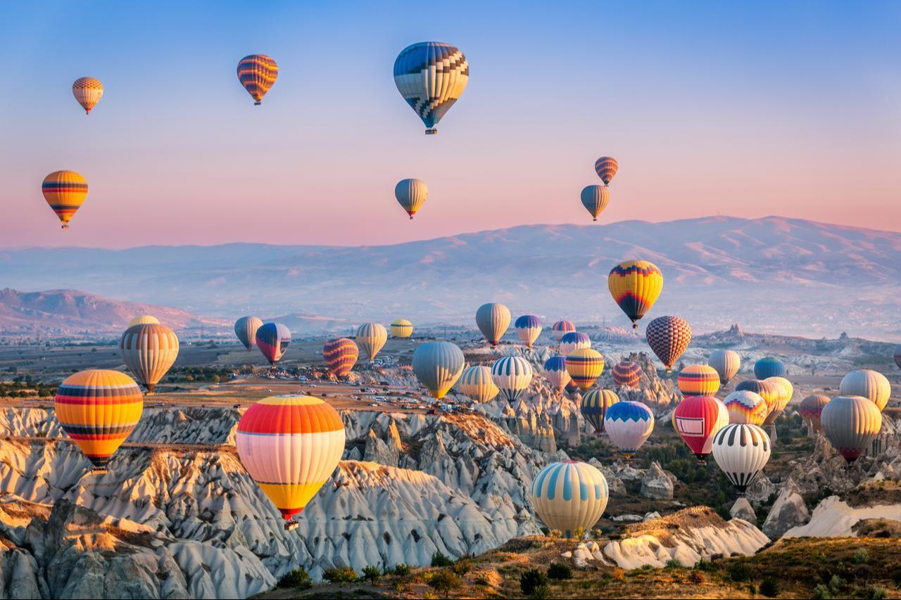 Overhead view of colorful hot air balloons floating across Cappadocia, Türkiye. (Adobe Stock Photo)