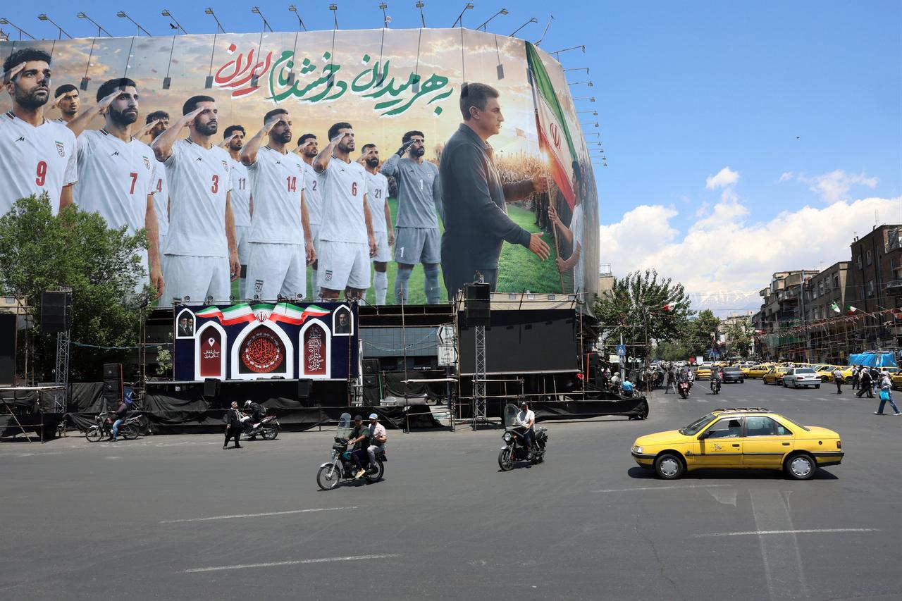 Vehicles drive past a huge billboard supporting Iran’s national football team in the upcoming 2026 World Cup, installed on a building at Enghelab Square in Tehran on May 18, 2026. (AFP Photo)
