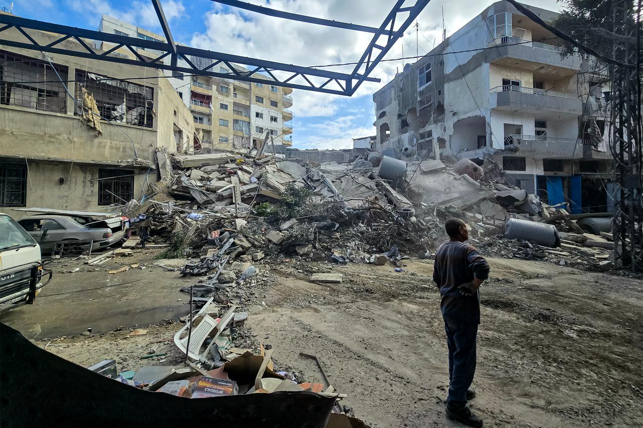 People stand by rubble and debris near damaged and collapsed buildings following overnight Israeli bombardment on Lebanon's southern city of Tyre, May 16, 2026. (AFP Photo)